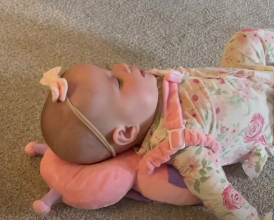 Baby lying on a pink pillow with floral outfit