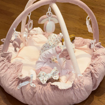 Pink baby play gym with toys on a wooden floor