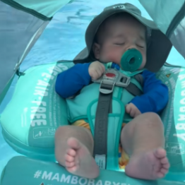 Baby in a blue life jacket and hat on a Mambobabyfloat with visible branding.