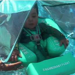 Child in a green inflatable baby float with a transparent canopy in water