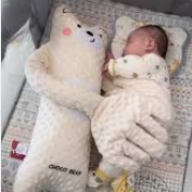 Baby lying on a bed with two large teddy bears