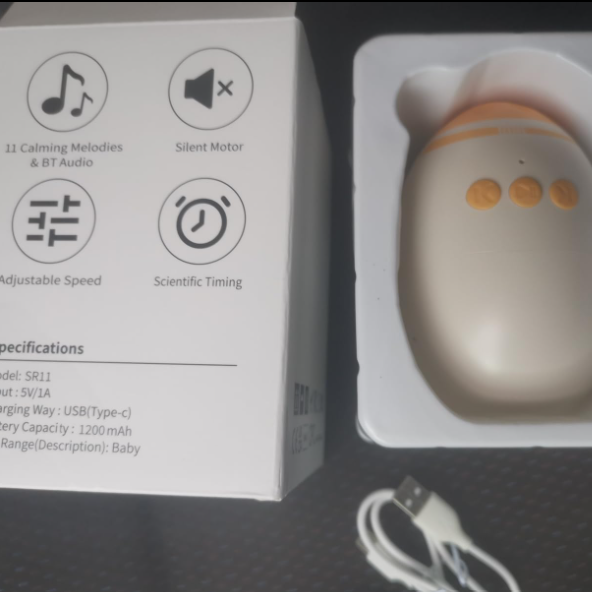 White electronic device with orange accents on a white stand next to its packaging box.
