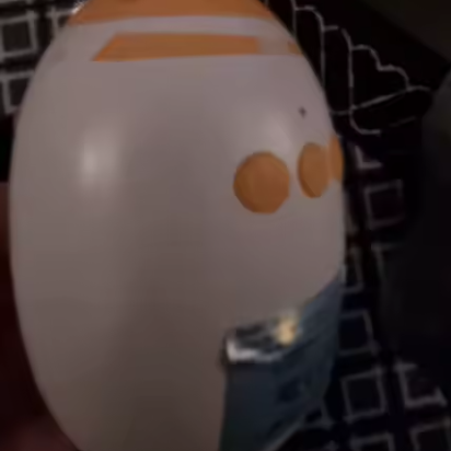 Round white object with orange accents on a dark patterned background