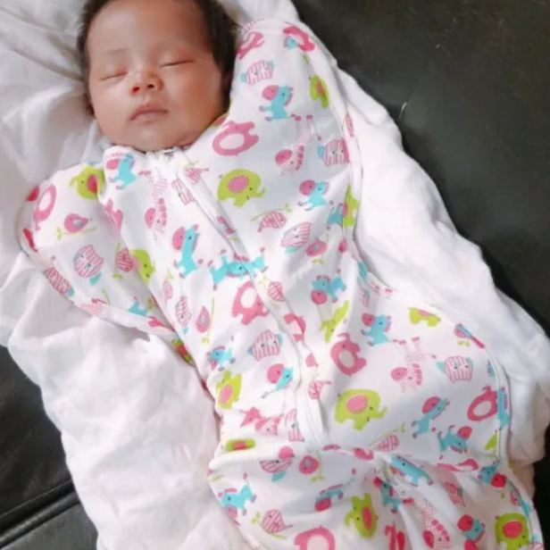 Newborn baby swaddled in a colorful blanket with cartoon patterns.